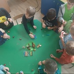 Grupa chłopców siedzi przy stoliku, na stole leżą kasztany i plastelina 