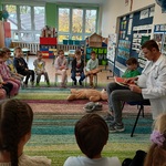 Przedszkolaki słuchają książki czytanej przez pana w farmaceutę.