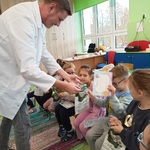 Pan farmaceuta wręcza dzieciom upominki i dyplomy.