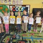 Grupa dzieci prezentuje swoje prace wykonane wg kodu binarnego.