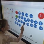 Dziewczynka układa kod strzałkowy na tablicy multimedialnej.