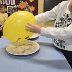 Chłopiec trzyma żółty balon nad talerzem z mieszanką pieprzu i cukru.