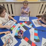 Dzieci siedzą przy stoliku i rysują mazakami kody dla robota Ozobot.