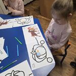 Dziewczynka obserwuje poruszającego się po kartce robota Ozobot.