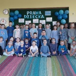 Dzieci z dwóch grup stoją przed tablica każdy z nim ma z niebieskie okulary własnoręcznie zdobione
