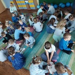 Dzieci siedzą na dywanie, podzielone na grupy układają puzzle