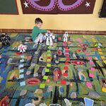 Chłopiec trzyma robota i ustawia go na drodze ułożonej z kolorowych karteczek.