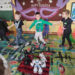 Dzieci trzymając się za ręce tańczą wokół robotów.