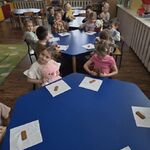 Dzieci z misiami siedzą przy stolikach_ przed kazdym dzieckiem leży ciasteczko na serwetce.