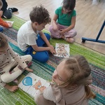 Starszaki na dywanie układają w parach puzzle.