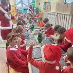 Dzieci siedzą przy stoliku, wykonują kule śnieżną 