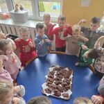 Dzieci stoją wokół stolika z upieczonymi piernikami.