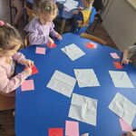 Dzieci rozsmarowują wazelinę na czerwonych karteczkach.