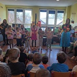 Kilkoro dzieci pod okiem muzyków uczy się tańca Hula.