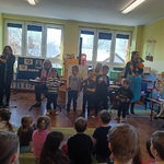 Przedszkolaki oglądają występ muzyków i kilkorga kolegów grających na instrumentach.