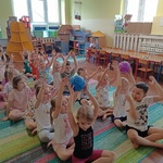 BOF 11 Przedszkolaki siedzą na podłodze w dwóch rzędach i przekazują kolejno  piłke górą.jpg